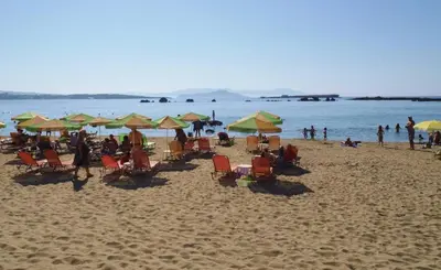 a group of people sitting on a beach with umbrellas at Atreas’ Art Studio in Chania Town