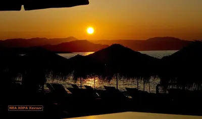 a sunset over a body of water with mountains at Atreas’ Art Studio in Chania Town