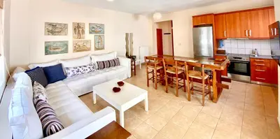 a living room with a white couch and a kitchen at Atreas’ Art Studio in Chania Town