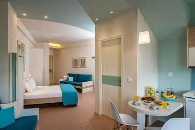 a room with a bed and a table and a kitchen at Studios Rika in Plataniás