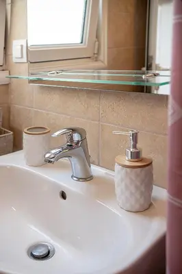 a bathroom sink with a faucet and two cups on it at Lavender suite sea view in Plataniás