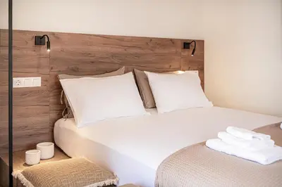 a bedroom with a white bed with a wooden headboard at Lavender suite sea view in Plataniás