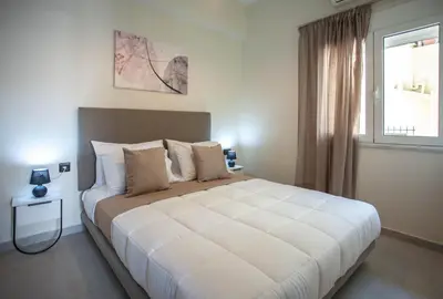 a bedroom with a large white bed with a window at Makel Apartment in Chania Town