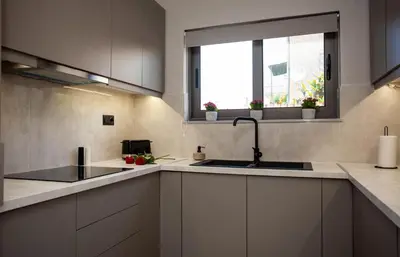 a kitchen with white cabinets and a sink and a window at Makel Apartment in Chania Town