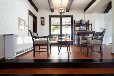 a living room with a table and chairs and a clock at Casa Bella Vista in Kalathas