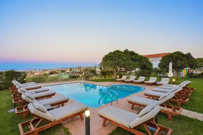 a group of lounge chairs and a swimming pool at Panthea Luxury Living in Kolymvari