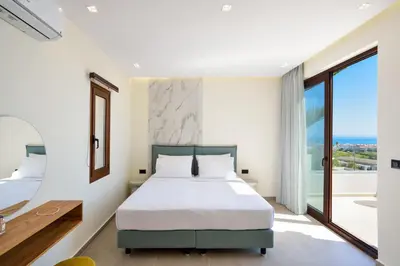 a bedroom with a bed and a large window at Panthea Luxury Living in Kolymvari
