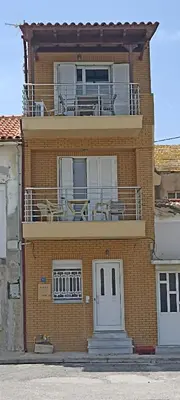 a building with a balcony with tables and chairs on it at Porta di Sabbia in Koum Kapi beach in Chania Town