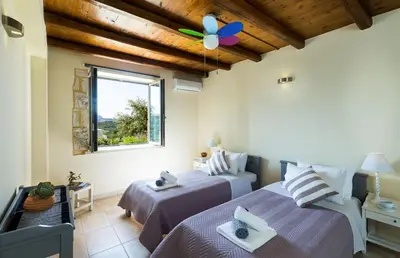 a bedroom with two beds and a window at Villa Asteriskos in Áyios Andhréas