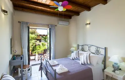a bedroom with a bed with a ceiling fan at Villa Asteriskos in Áyios Andhréas