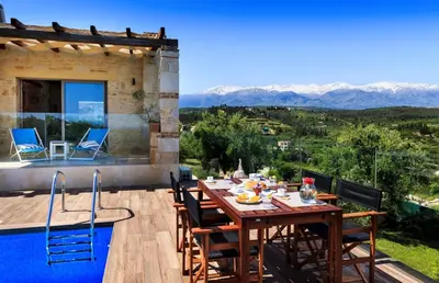 a wooden table and chairs on a patio with a view at Villa Asteriskos in Áyios Andhréas