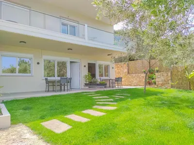 a house with a green lawn in front of it at Renovated apartment 3- Platanias in Plataniás
