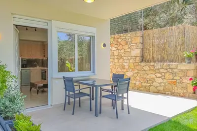 a patio with a table and chairs and a stone wall at Renovated apartment 3- Platanias in Plataniás
