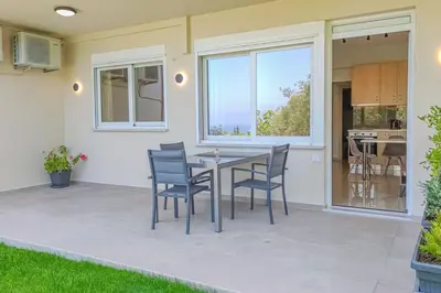 a patio with a table and chairs in front of a house at Renovated apartment 2 -Platanias in Plataniás