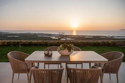 a table and chairs with the sunset in the background at GG Villas Falassarna in Chania Town