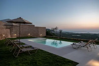 a swimming pool with two chairs and an umbrella at GG Villas Falassarna in Chania Town