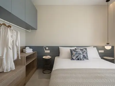 a bedroom with a bed and a rack of clothes at GG Villas Falassarna in Chania Town