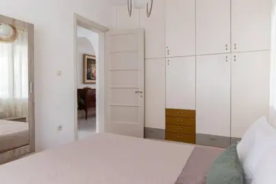 a white bedroom with a bed and a mirror at Casa Valore central with parking by 8essentially in Chania Town