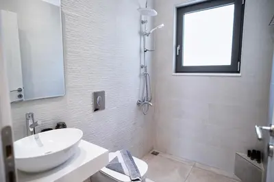 a white bathroom with a sink and a toilet at Sweven boutique apartments in Souda
