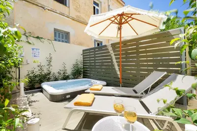 a patio with a hot tub and an umbrella at Casa Verde Chania in Chania Town