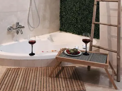 a bath tub with two glasses of wine and a table with a plate of food at E&G Relax Homes-C in Kissamos