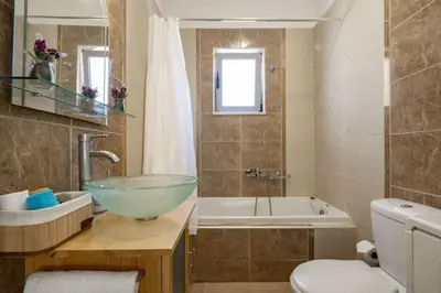 a bathroom with a bowl sink and a tub at Christini Cozy Apartment in Souda