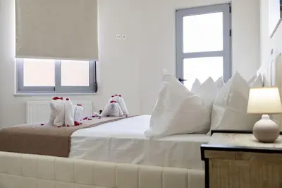 a white bedroom with a large white bed with white pillows at Christini Cozy Apartment in Souda
