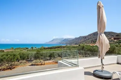 an umbrella on a balcony with a view of the ocean at Isabel Artemis Crete - Luxury Sea Views Villas in Nopíyia