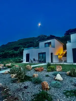 a large white house with rocks in front of it at Isabel Artemis Crete - Luxury Sea Views Villas in Nopíyia