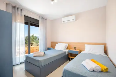 a bedroom with two beds and a window at Isabel Artemis Crete - Luxury Sea Views Villas in Nopíyia