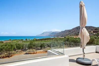 an umbrella on a balcony with a view of the ocean at Isabel Artemis Crete - Luxury Sea Views Villas in Nopíyia