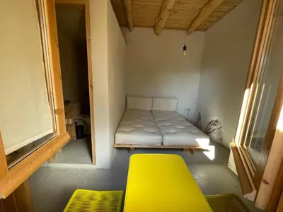 a small room with a bed and a yellow chair at Petres old village house in Áyios Ioánnis