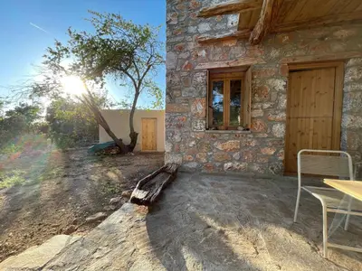 a stone building with a table and chairs in front of it at Petres old village house in Áyios Ioánnis