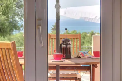 a table with a coffee maker on top of a balcony at Mabech Villa in Plataniás