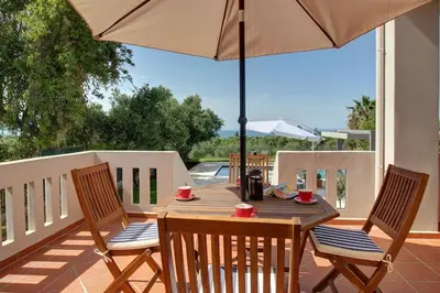 a wooden table with two chairs and an umbrella at Mabech Villa in Plataniás