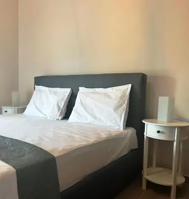 a bed with white pillows and a side table at Korina's Apartment in Daratso