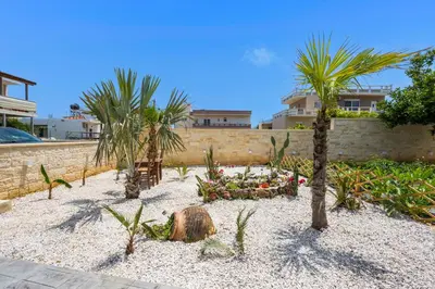 a garden with palm trees and a retaining wall at Garden Villa Chania in Chania Town