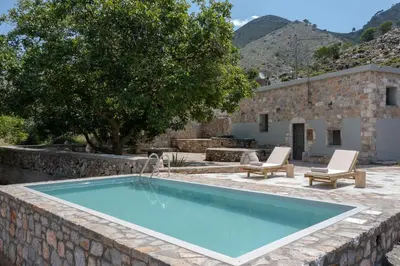 a swimming pool in a stone wall next to a house at Nomas Home Imbros in Khóra Sfakíon
