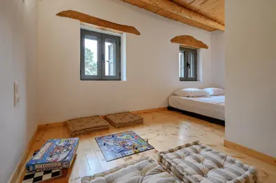 a room with a bed and a couch and windows at Nomas Home Imbros in Khóra Sfakíon