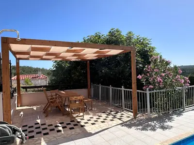 a wooden pergola with a table and chairs on a patio at Villa Albama in Darmarochori