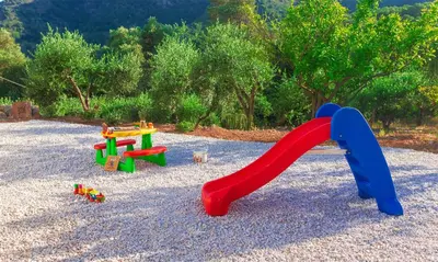 a playground with a slide and toys on gravel at Archontissa Kakodiki - Paleochora in Áyioi Theódhoroi