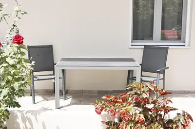 a table and chairs in a patio with flowers at Adriana Apartment in Agia Marina Nea Kydonias