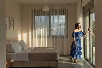 a woman in a blue dress standing in a bedroom at Oliva Verde Residences in Galatás