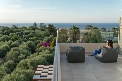 a woman sitting on the balcony of a house at Oliva Verde Residences in Galatás