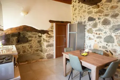 a kitchen and dining room with a wooden table and chairs at Alegria stone house in AmigdhalokeFálion