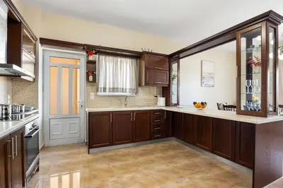 a large kitchen with wooden cabinets and a window at Patelakis Apartment near the Beach in Chania Town