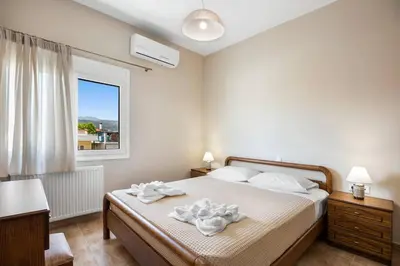 a bedroom with a bed with white sheets and a window at Patelakis Apartment near the Beach in Chania Town