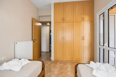 two beds in a room with wooden cabinets at Patelakis Apartment near the Beach in Chania Town