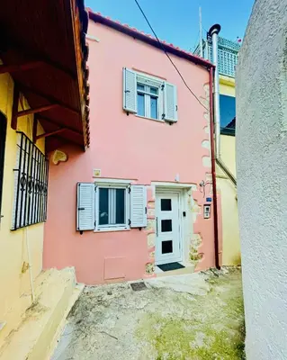 a pink house with two windows and a door at Julia's cottage in Kalyves