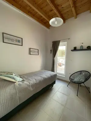 a bedroom with a bed and a chair and a window at Julia's cottage in Kalyves